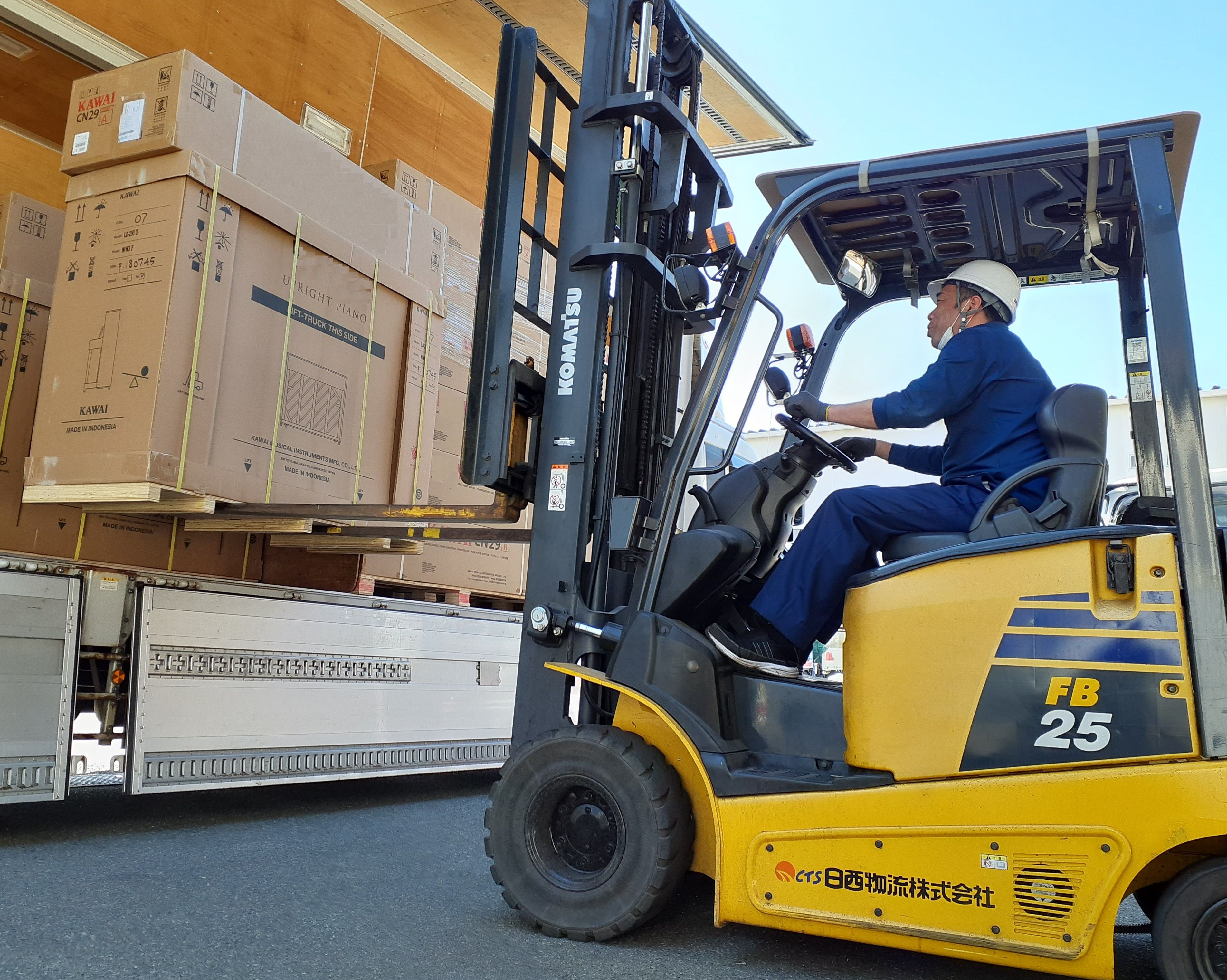 スタッフがフォークリフトでトラックに積荷を積み入れている写真